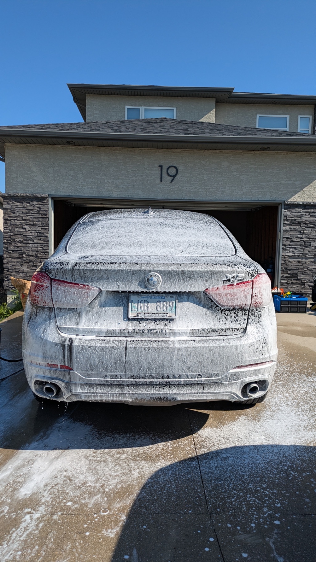 BMW X5 buried in foam, sun-lit and dripping clean